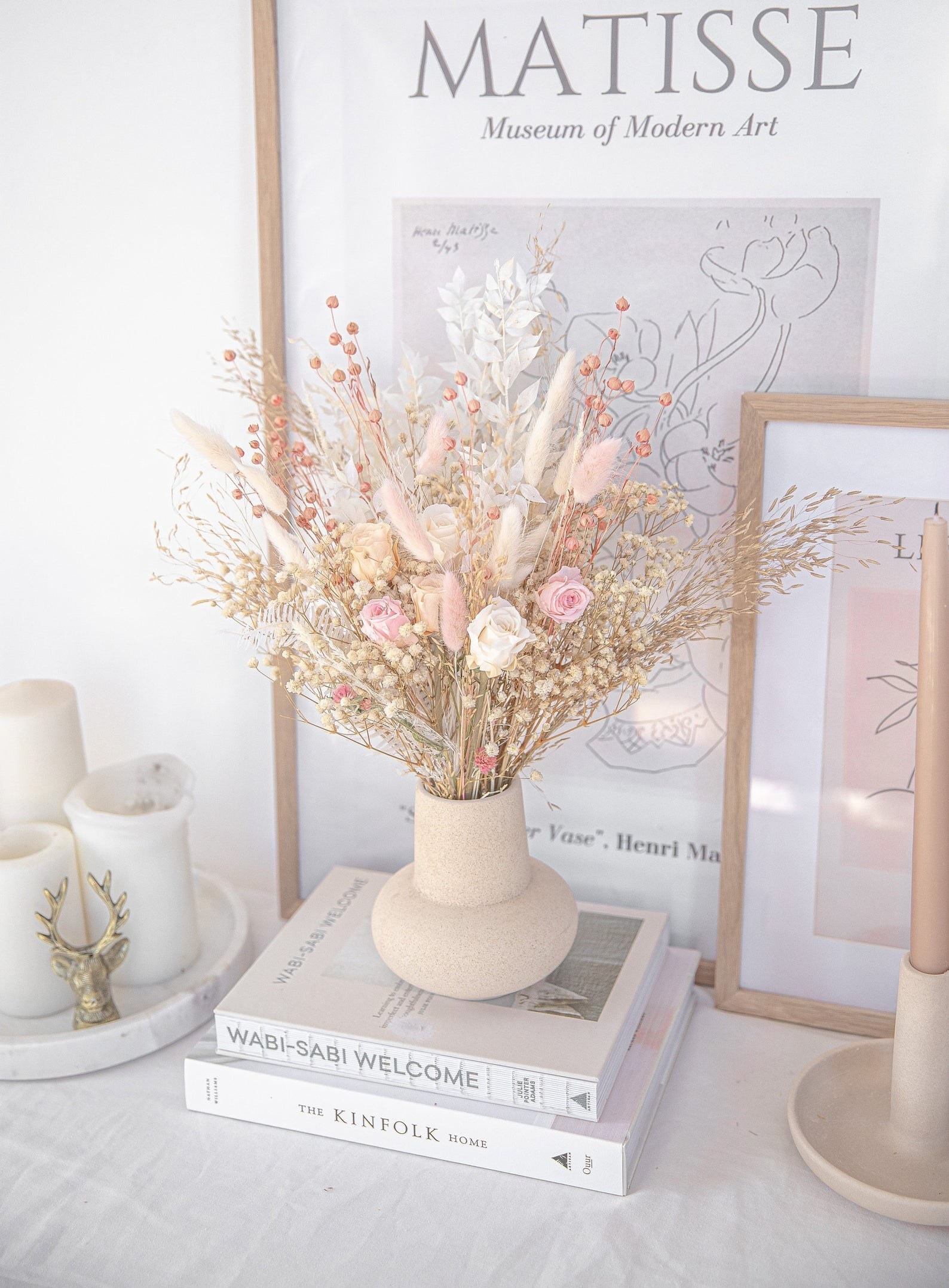 the bouquet in a vase atop a stack of books and next to some candles