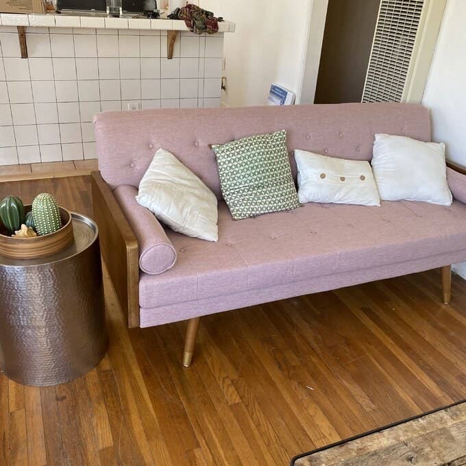 The fabric sofa in light pink with wooden frame and pin legs