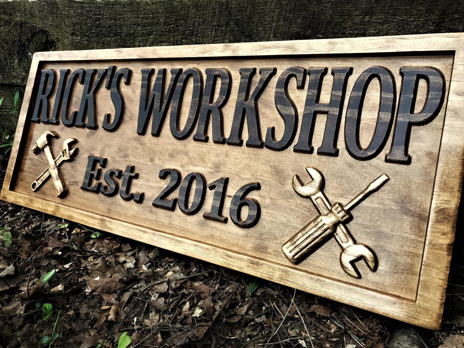 a wooden sign that says rick&#x27;s workshop est 2016 with a images of tools on each end