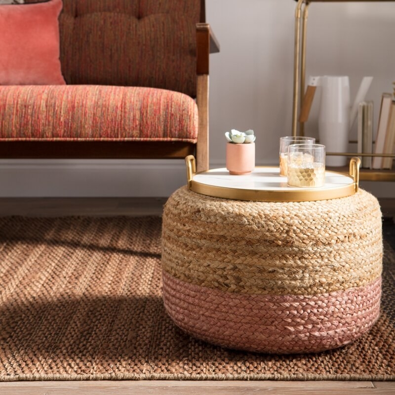 round pink and beige pouf on the floor with a tray of drinks on top