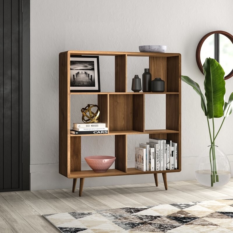 geometric wood bookcase with splayed legs, with books and decor on the shelves