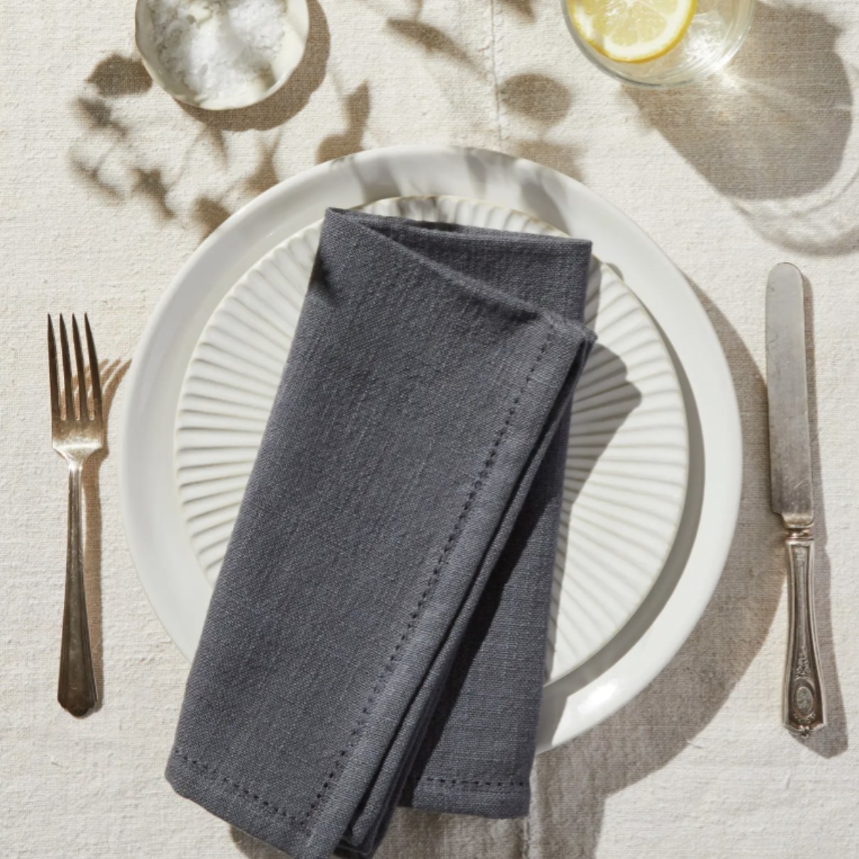a grey cotton napkin folded over a plate set up