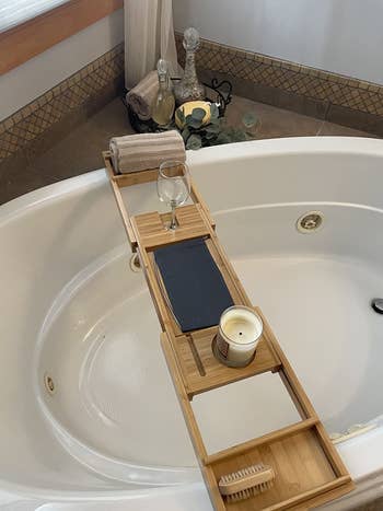 reviewer showing the bamboo tray placed on their round tub 