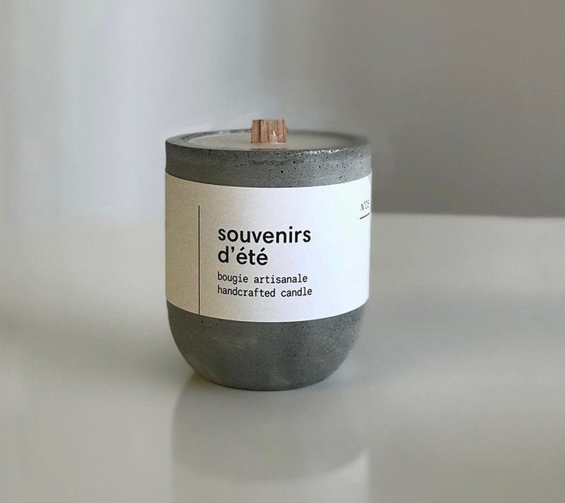 A candle with a wooden wick inside a reusable concrete container