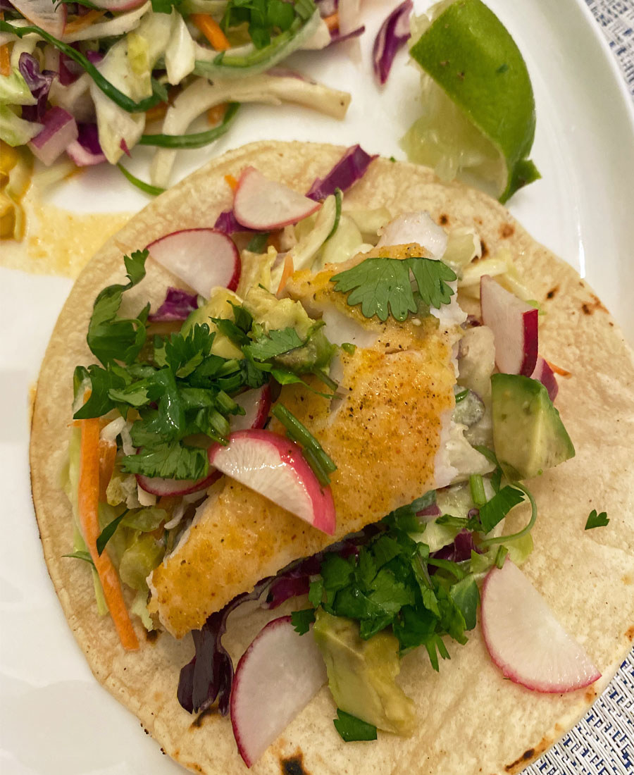 Crispy fish tacos topped with avocado, cilantro, and slaw.