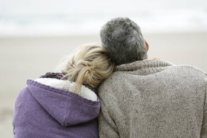 a couple leaning their heads on each other staring at the ocean