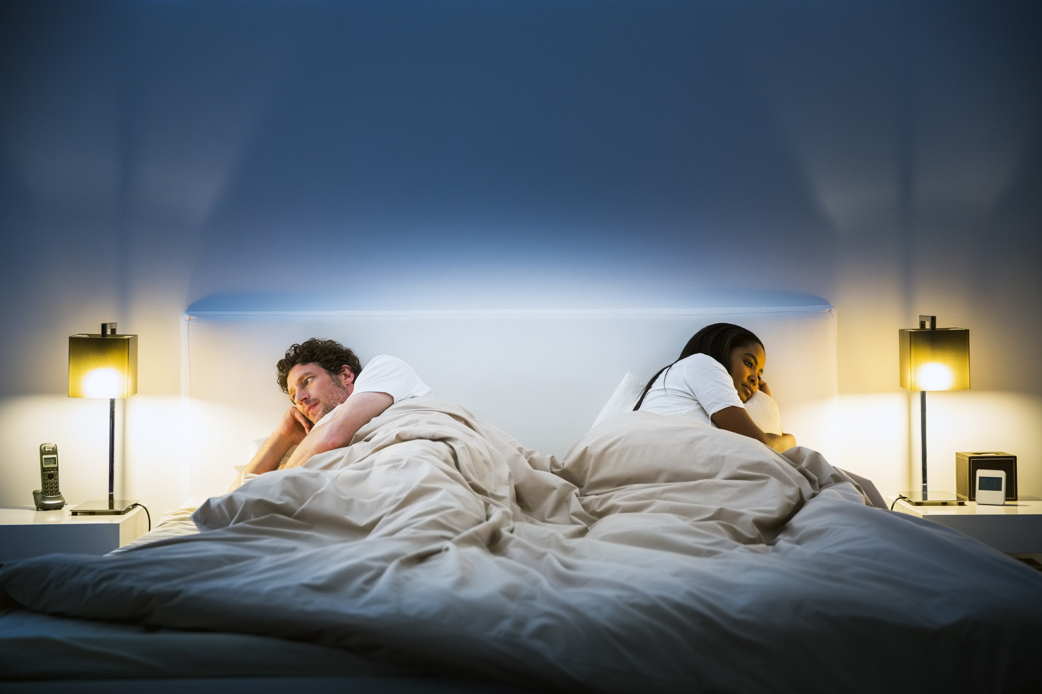 a couple looking away from each other in bed