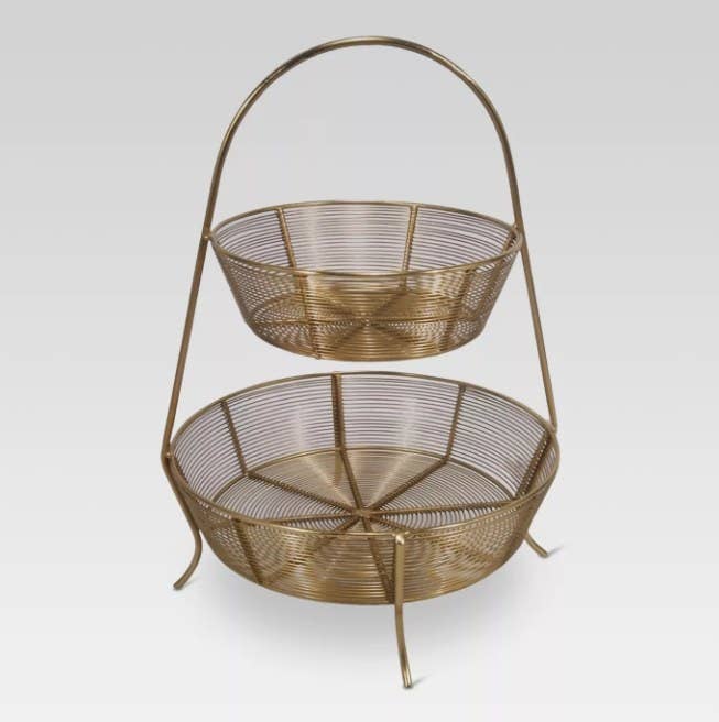 A two-tier, gold-plated wire basket that can be used to store fruit and vegetables