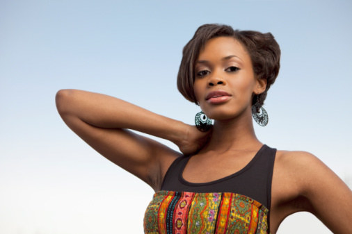 A woman standing with her arm bent, emphasizing her elbow.