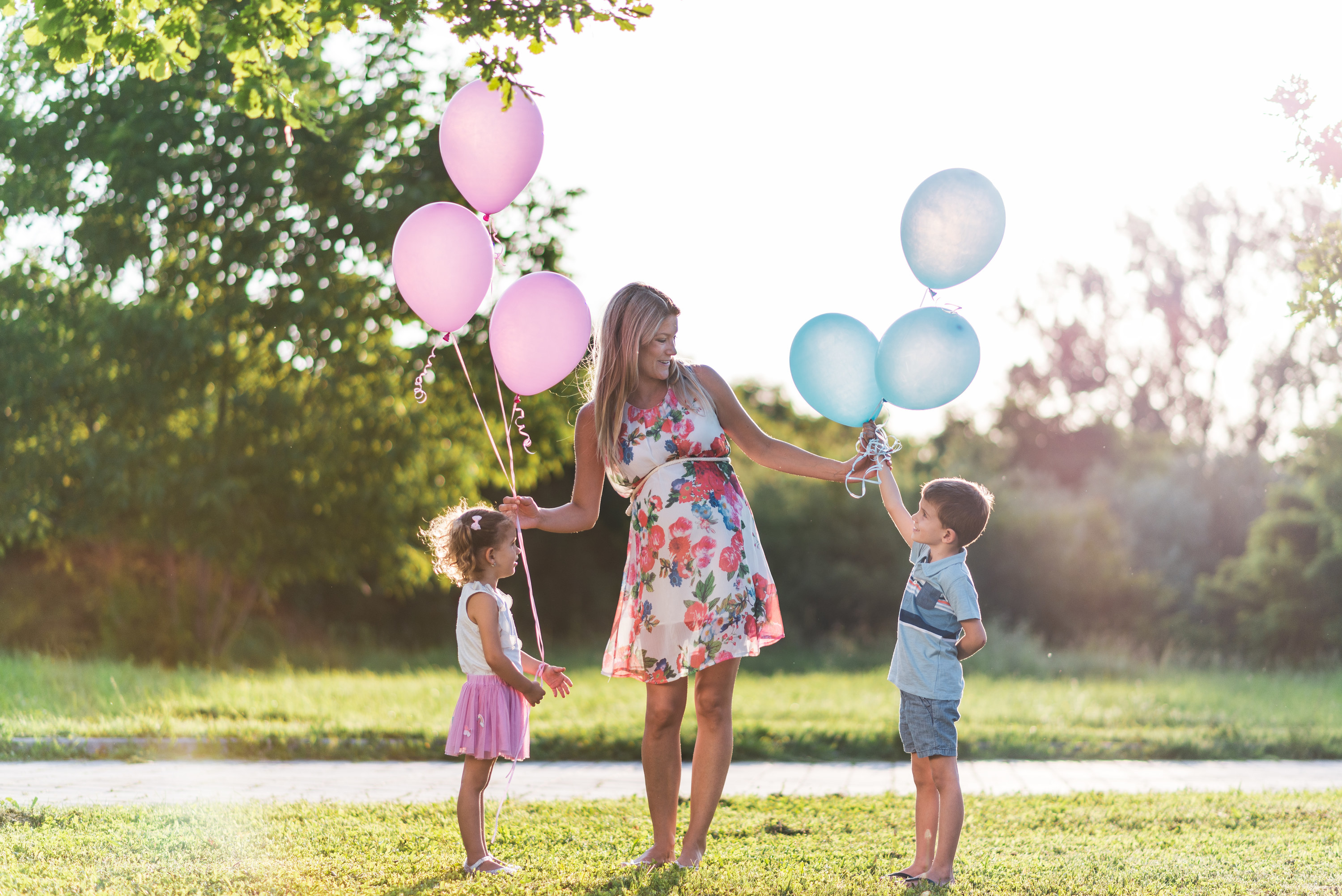 a woman holding pink and blue balloons