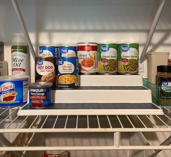 Reviewer&#x27;s picture of the three-level organizer being used for cans in their pantry 