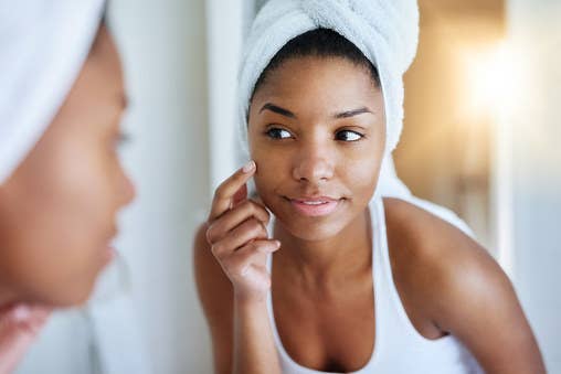 Woman with her hair in a towel looks in the mirror.