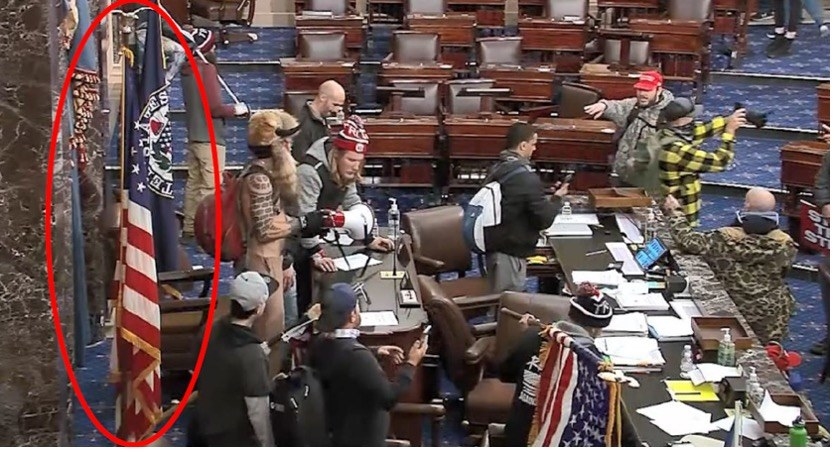 Several rioters stand in the US Senate chamber taking photos 