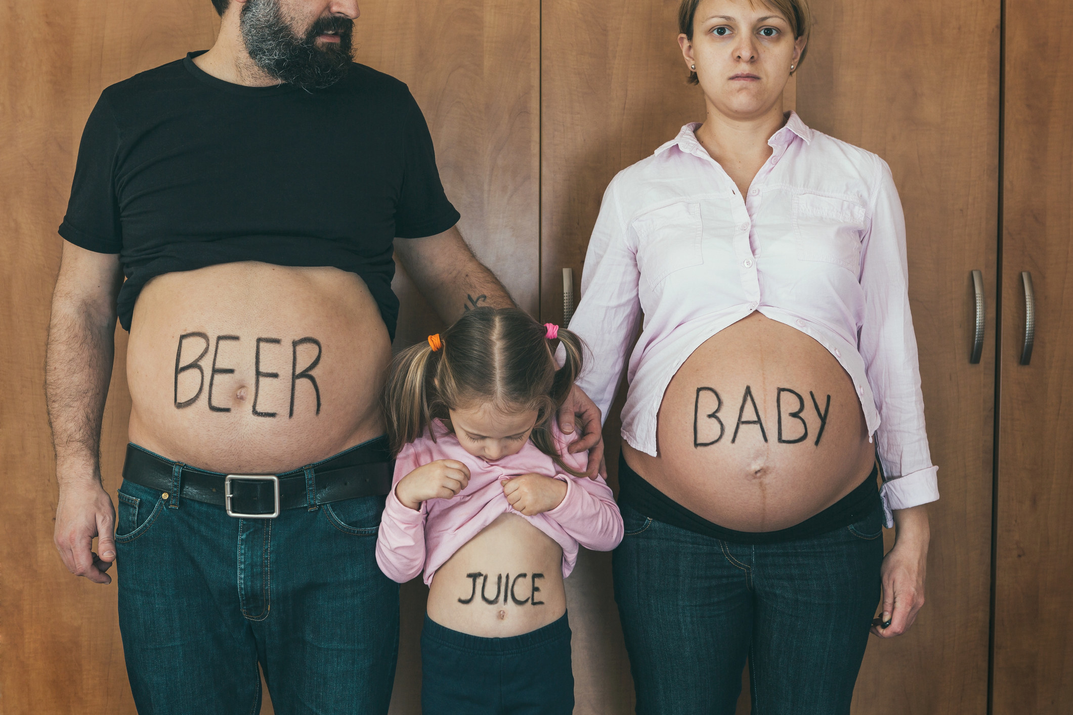 straight people doing a baby announcement one stomach full of beer one juice and one baby