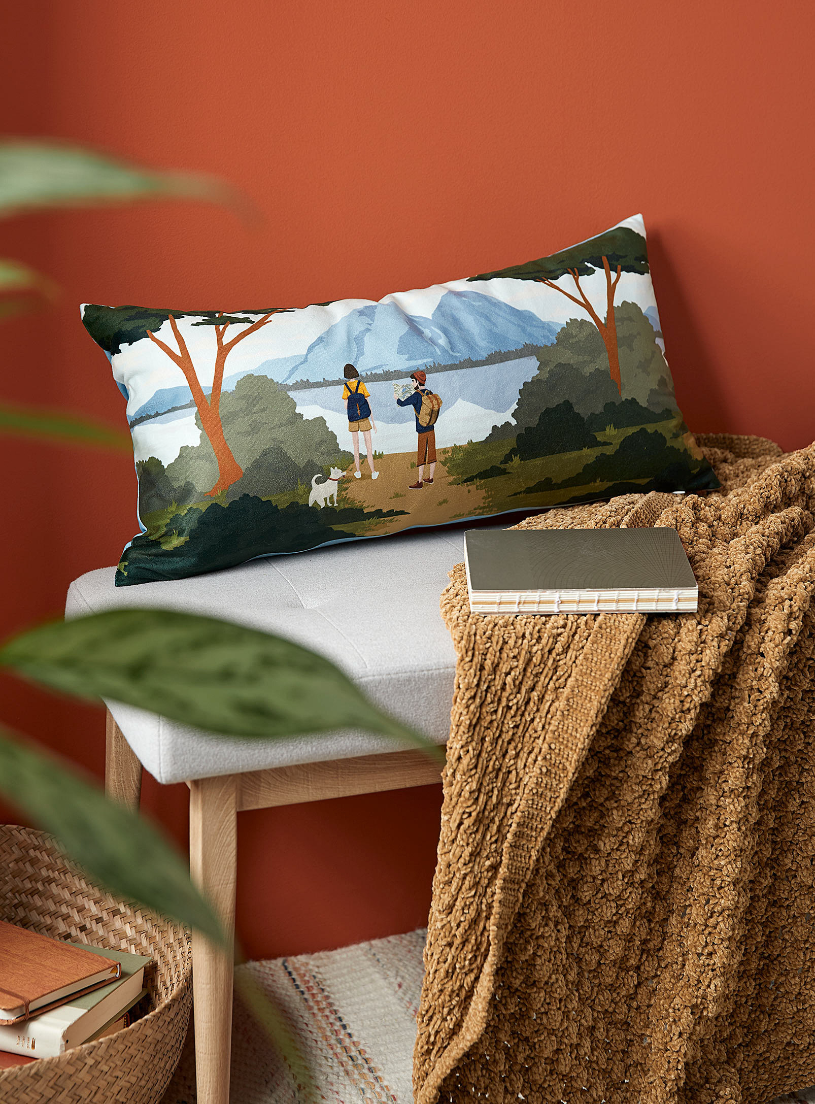the hike pillow on a bench outdoors with a blanket and a book