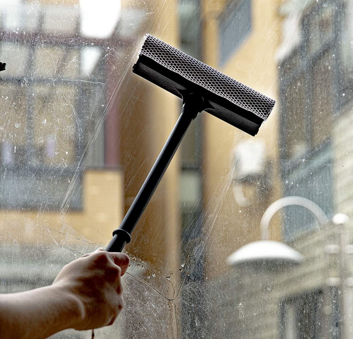 person cleaning a glass window with the squeegee