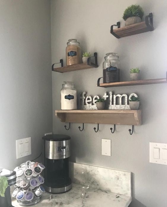 Reviewer&#x27;s picture of the three wooden wall shelves holding kitchen jars and decorative signs