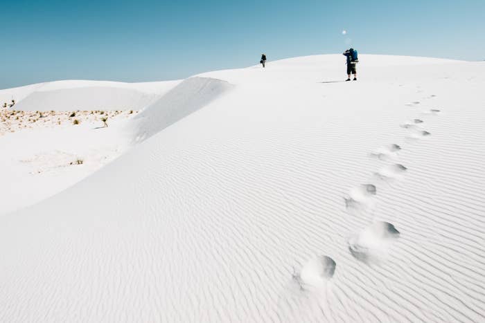 People hiking on white sand in giant dunes