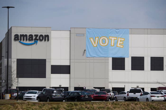 A giant flag that reads &quot;Vote&quot; hangs over the side of a building beside the Amazon logo