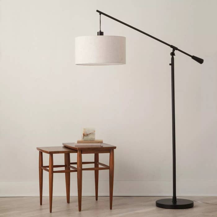 The pendant floor lamp with a black base and white lamp shade in a living room