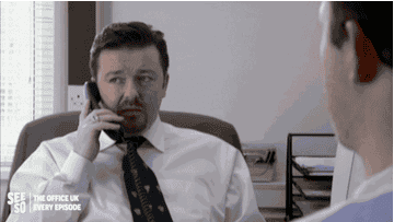 Ricky Gervais as David Brent gesturing at an employee to go type