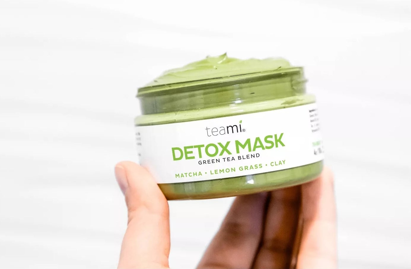 A model holding a jar filled with the detox mask