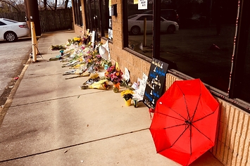 A red umbrella and memorials outside a storefront