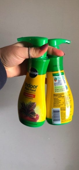 User holds two bottles of plant food with pump dispenser.