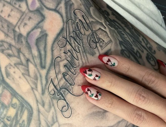 Kourtney manicured nails, which have hearts, next to the tattoo