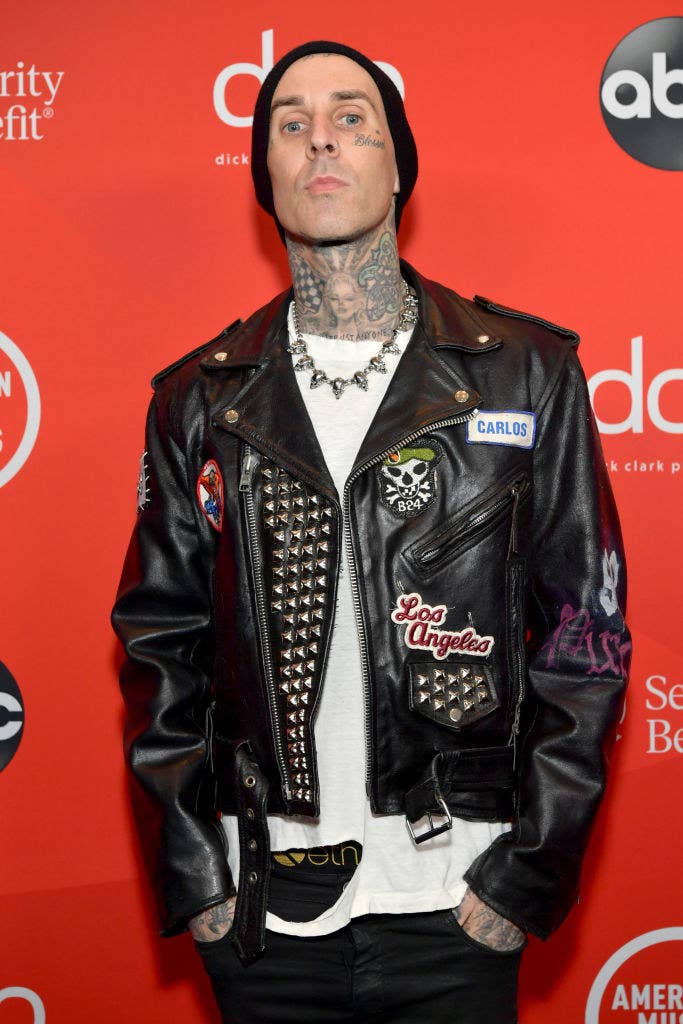 Travis at an event wearing a leather jacket and showing off his neck tattoos