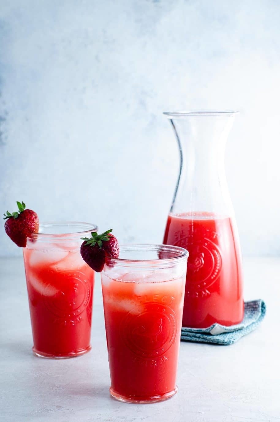 A carafe and two glasses of strawberry agua fresca