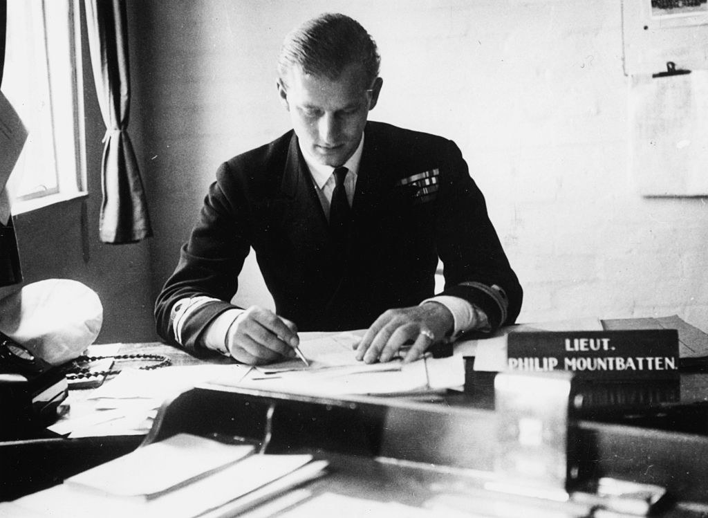 Prince Philip sitting at a desk in his military uniform