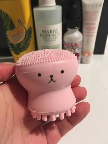 a reviewer holding the light pink jelly fish facial brush
