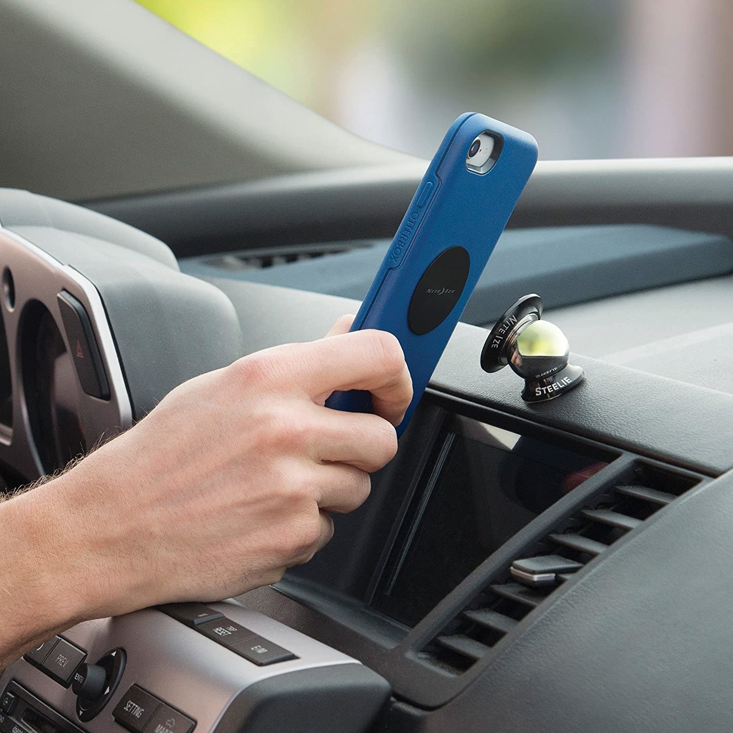 A person attaching their phone to a swiveling phone mount on their dashboard