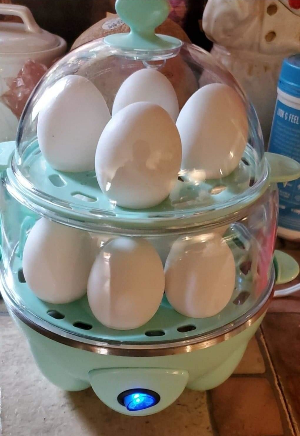 A reviewer uses the teal-colored cooker to boil a dozen white eggs