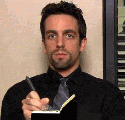 Ryan from &quot;The Office&quot; looking at the camera and writing in a notebook