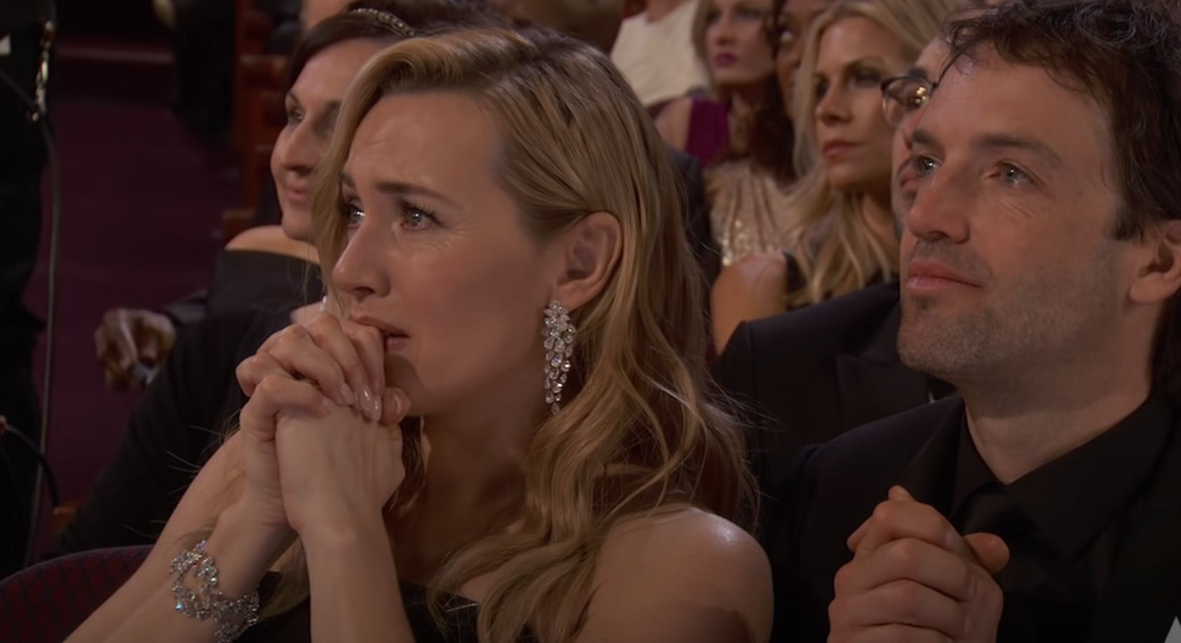 Kate clasping her hands to her face