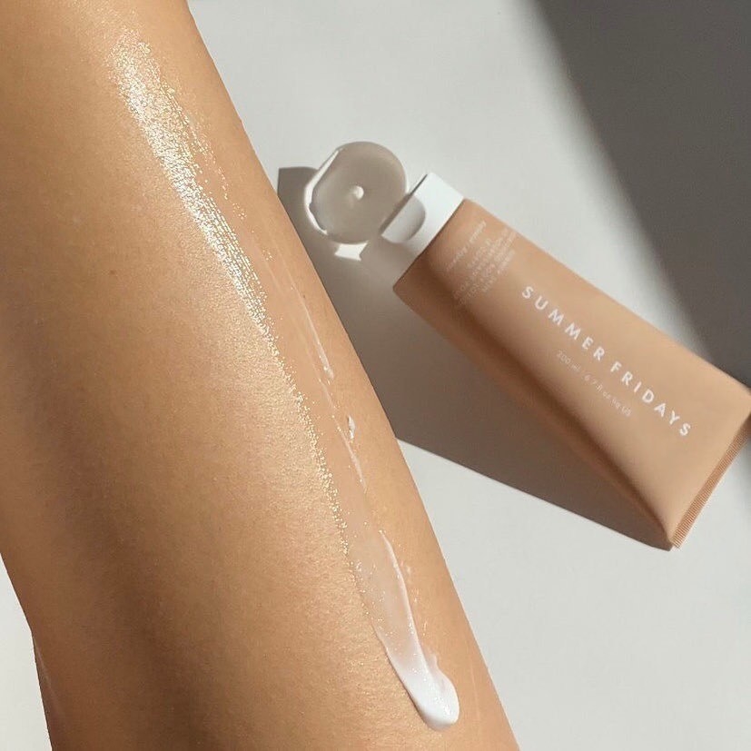 A person&#x27;s leg with cream on it and a tube of body lotion next to it