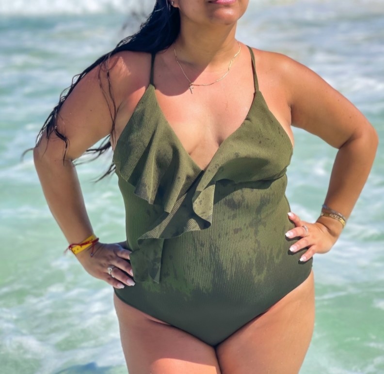 A reviewer wearing the suit in green in the ocean 
