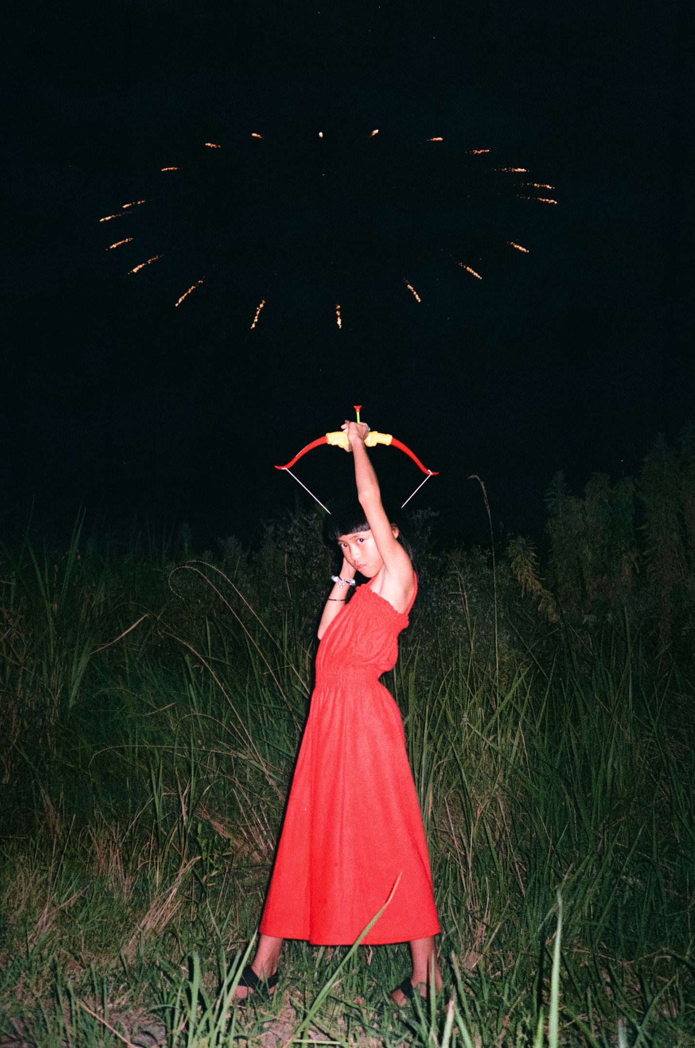 The photographer&#x27;s daughter shooting an arrow upwards into fireworks