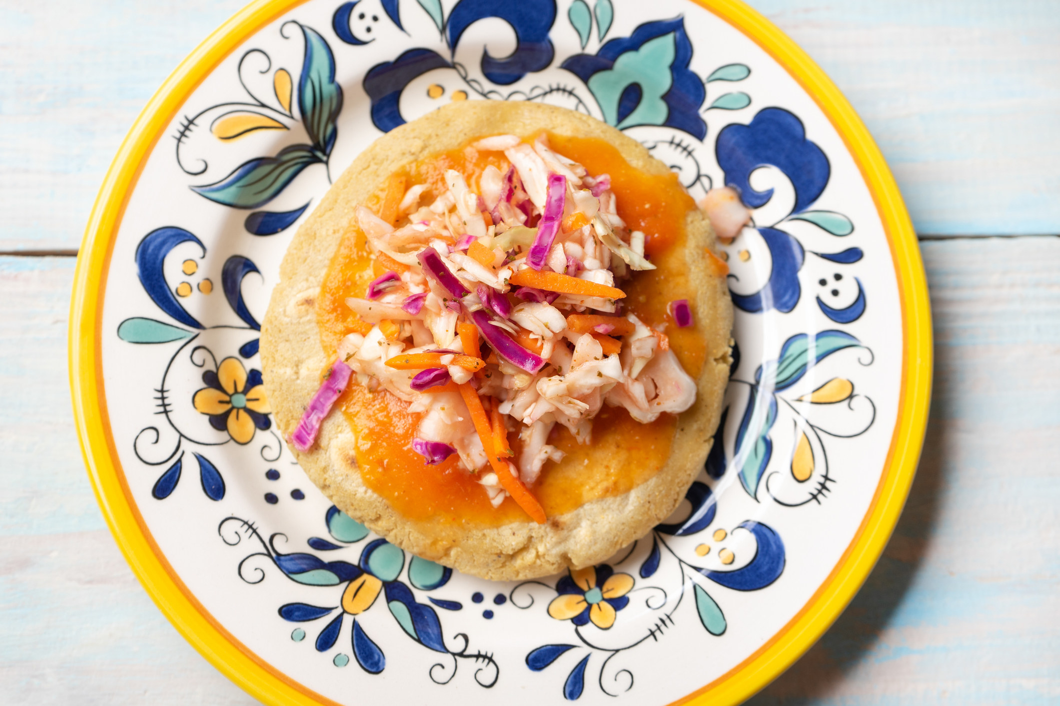 A Venezuelan pupusa topped with pickled cabbage.