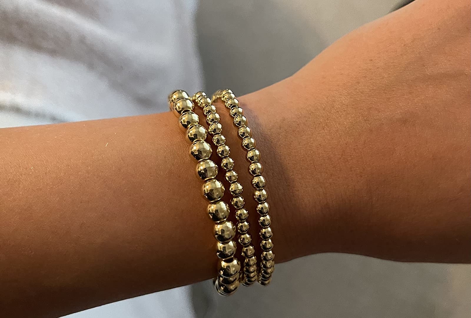 a reviewer wearing three gold beaded bracelets