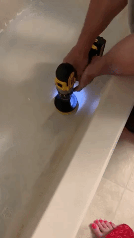 Reviewer using the brush to clean grime out of a tub 