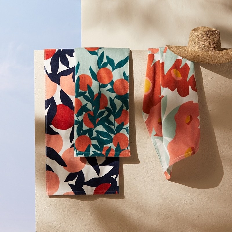 Three hanging towels with vibrant floral patterns on each