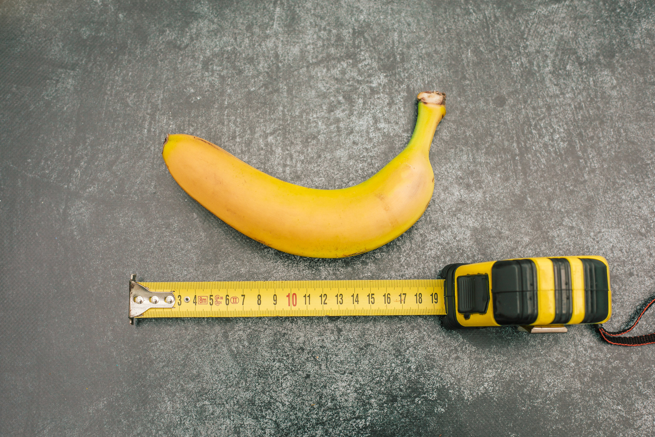 uma banana ao lado de uma fita métrica