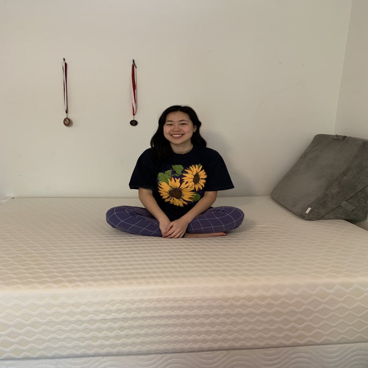 writer sitting on mattress with back wedge in the background