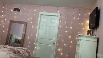 The lights vertically hung and flickering in a pattern against a pink bedroom wall 