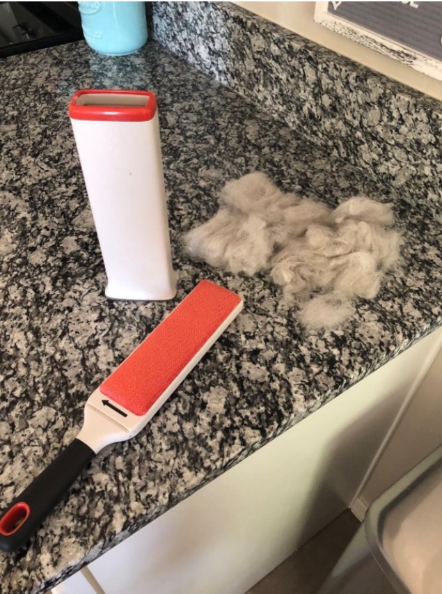 The lint brush beside a pile of pet hair it removed