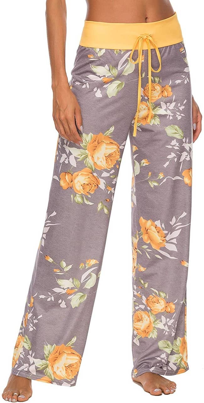 model wearing wide leg gray and yellow floral pants with yellow drawstring waistband