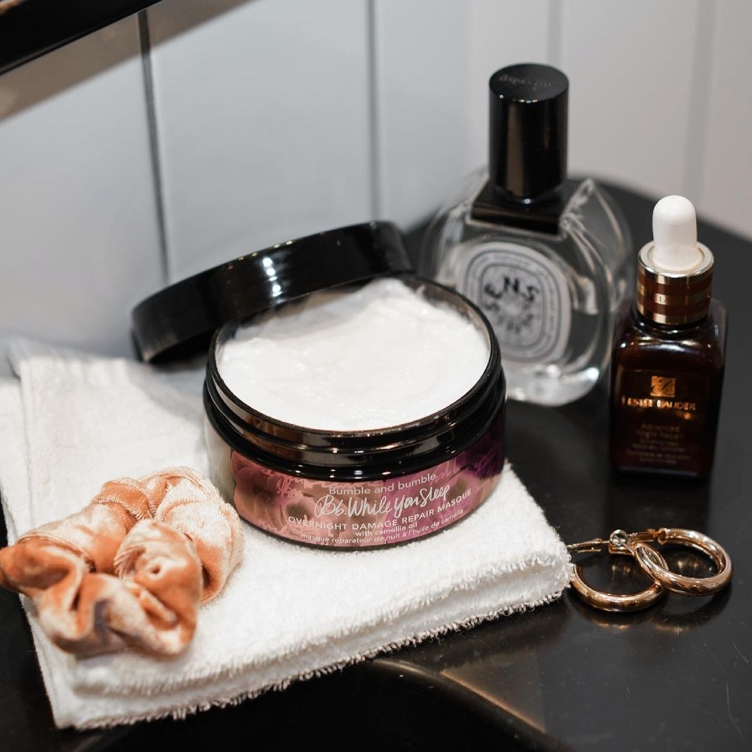 A jar of the hair mask on a vanity next to other skincare and jewellery